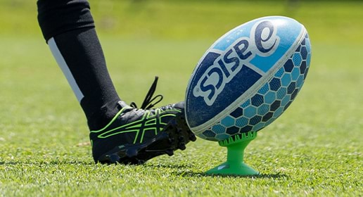 close up of foot in football shoe and about to kick a rugby ball
